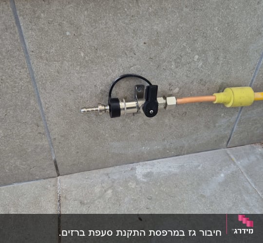 שסתום גז מחובר לצינור כתום על קיר
